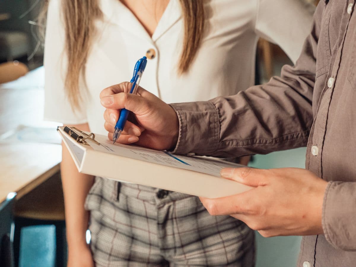 A close-up of someone writing on a clipboard document